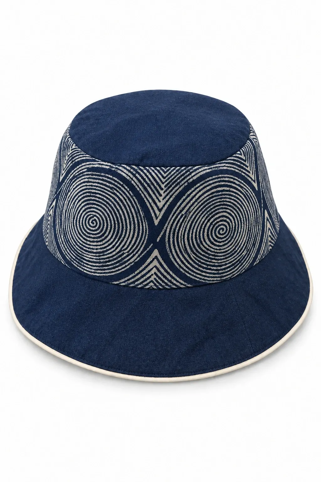 Indigo cotton bucket hat with cream Wotuo batik spirals, a plain indigo top and flared brim with ivory edging, on white.