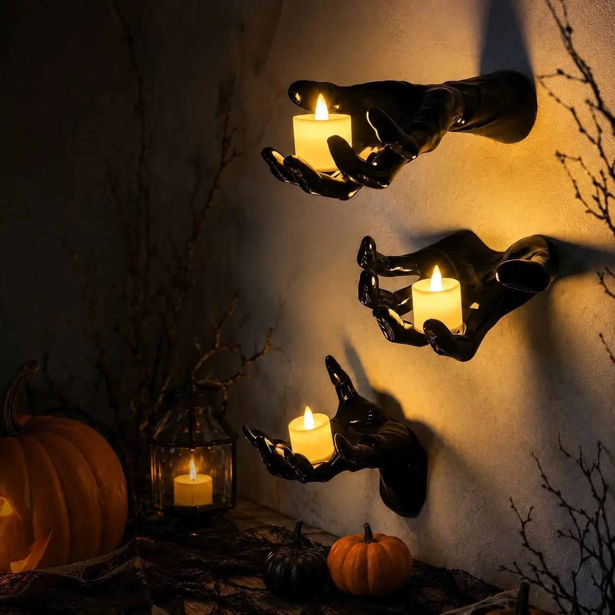 Three gothic wall-mounted black hands holding glowing LED candles in a Halloween display