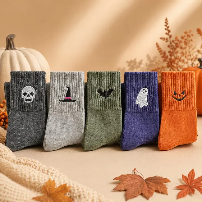 Five Halloween stockings, arranged with pumpkins and autumn leaves.
