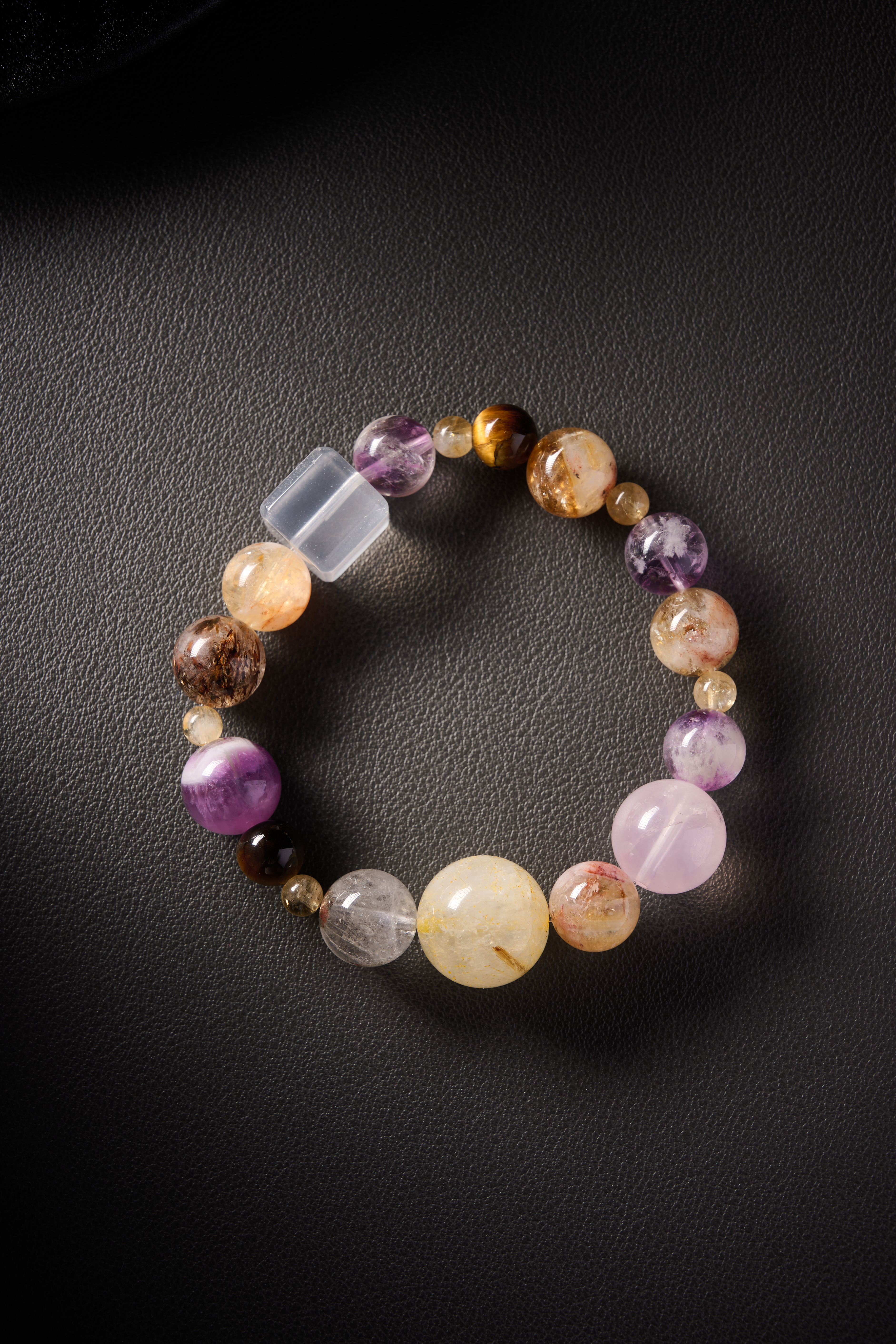 Hero image – multi-crystal energy bracelet with clear quartz, amethyst, citrine, rose quartz, tiger’s eye and rutilated quartz on dark background.