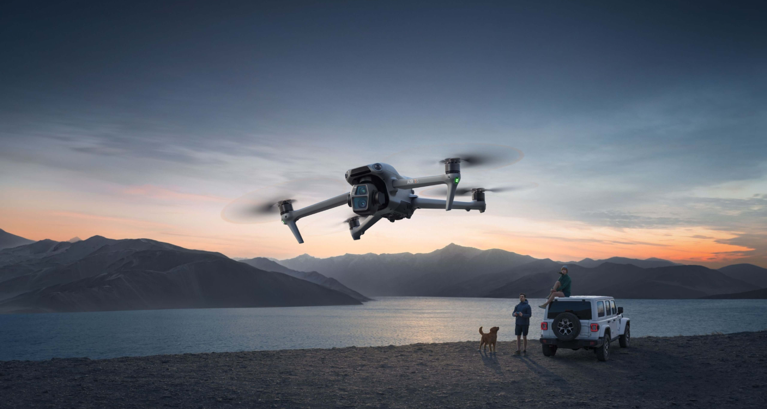 A man operates a DJI Air 3S by a lake.