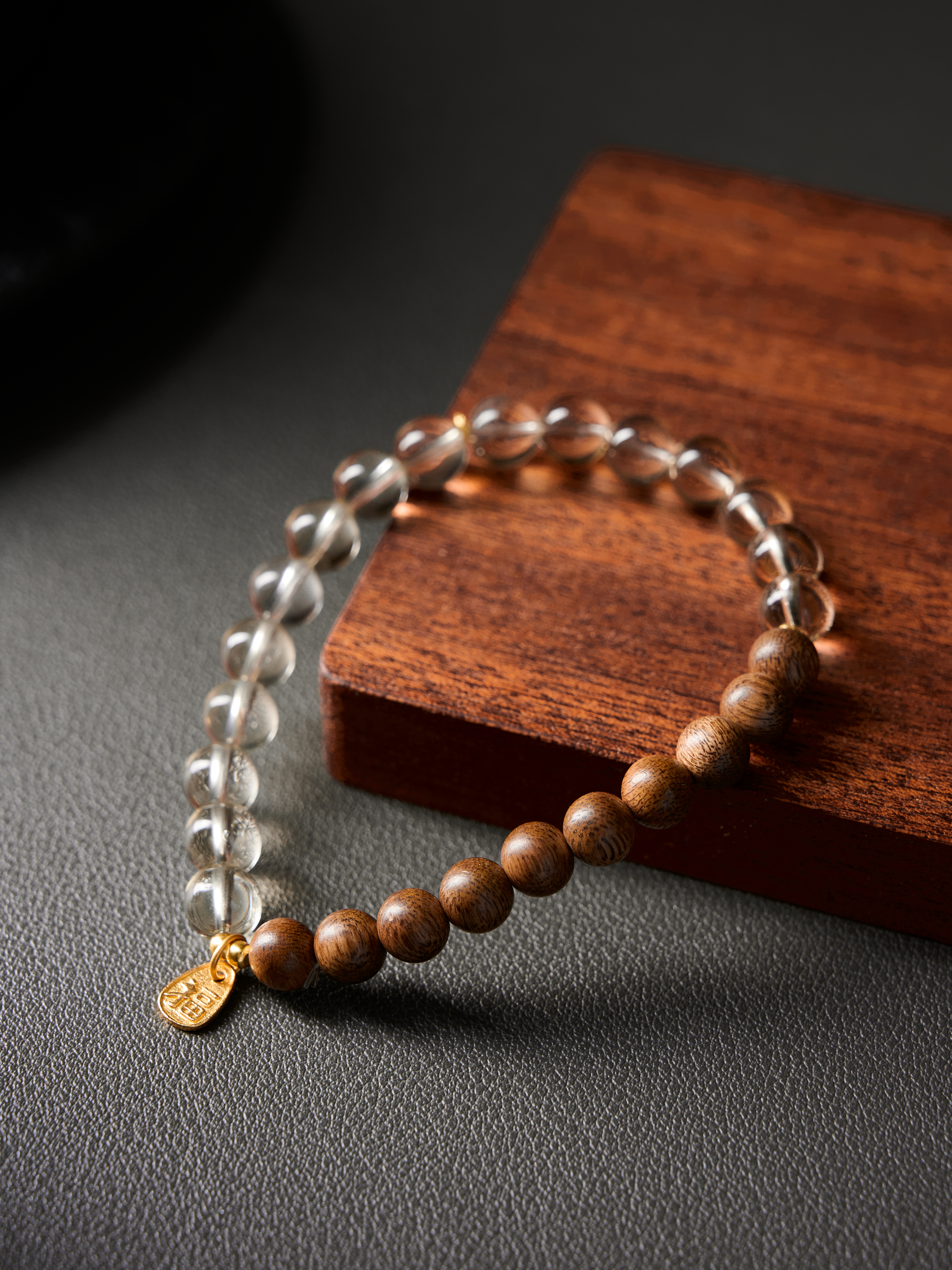 Angled side shot highlighting polish and spacing on hand-strung sandalwood–crystal bracelet