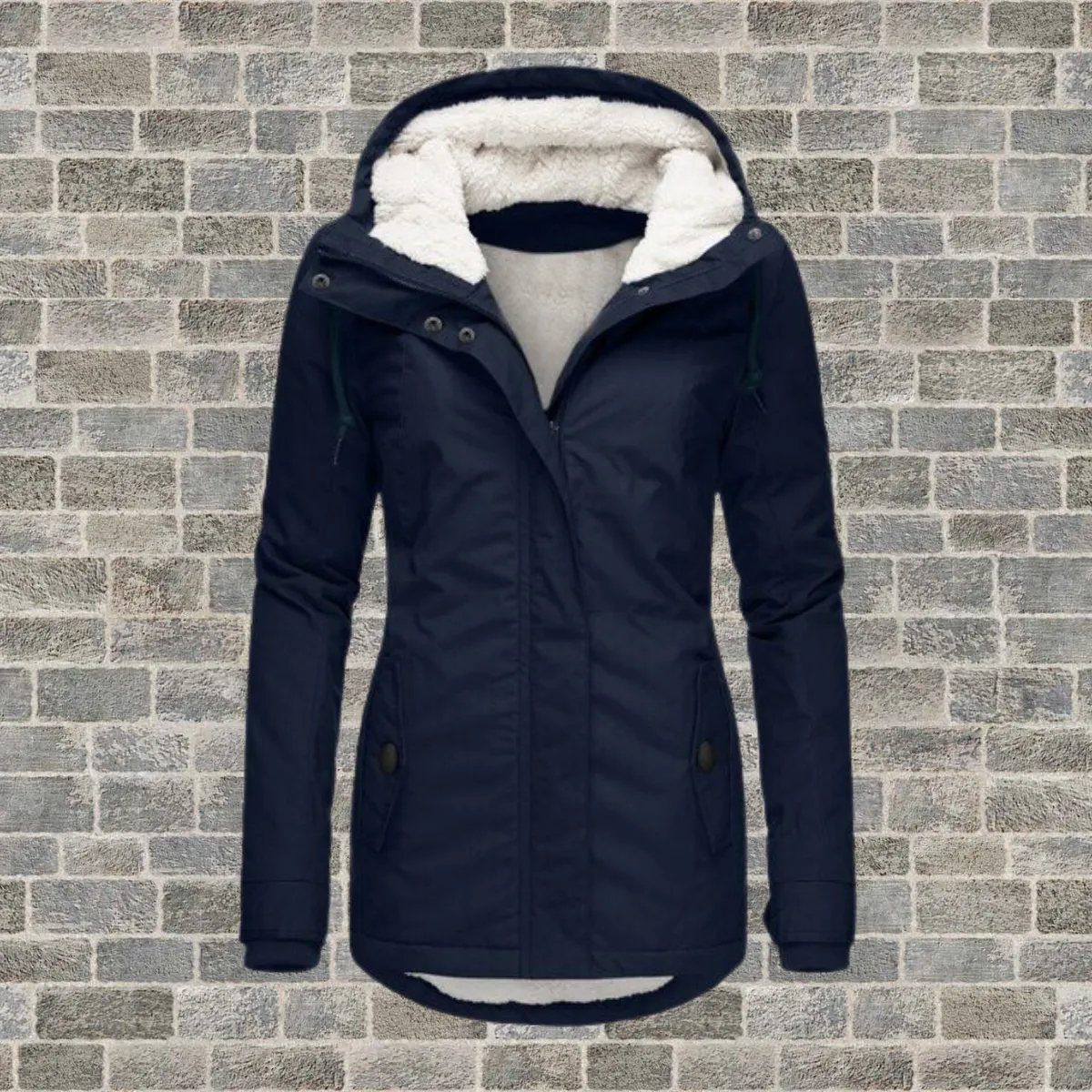 Marineblaue Winterjacke mit weißer Sherpa-gefütterter Kapuze, Reißverschluss vorne, Druckknöpfen und zwei Seitentaschen, präsentiert vor einem grauen Backsteinmauer-Hintergrund