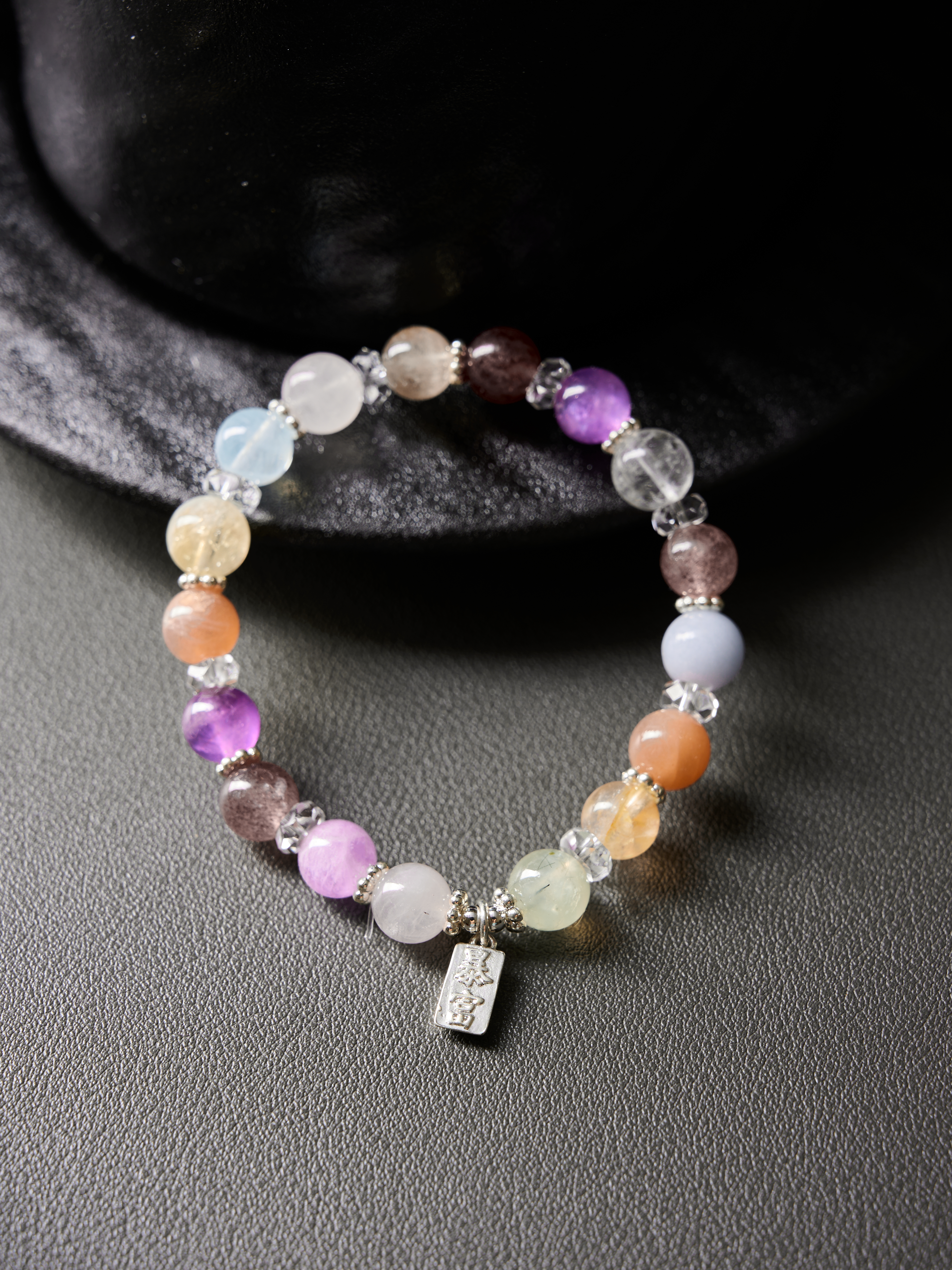 Flat lay circle on wooden tray showing soft palette: amethyst purple, aquamarine blue, sunstone peach with clear-quartz accents
