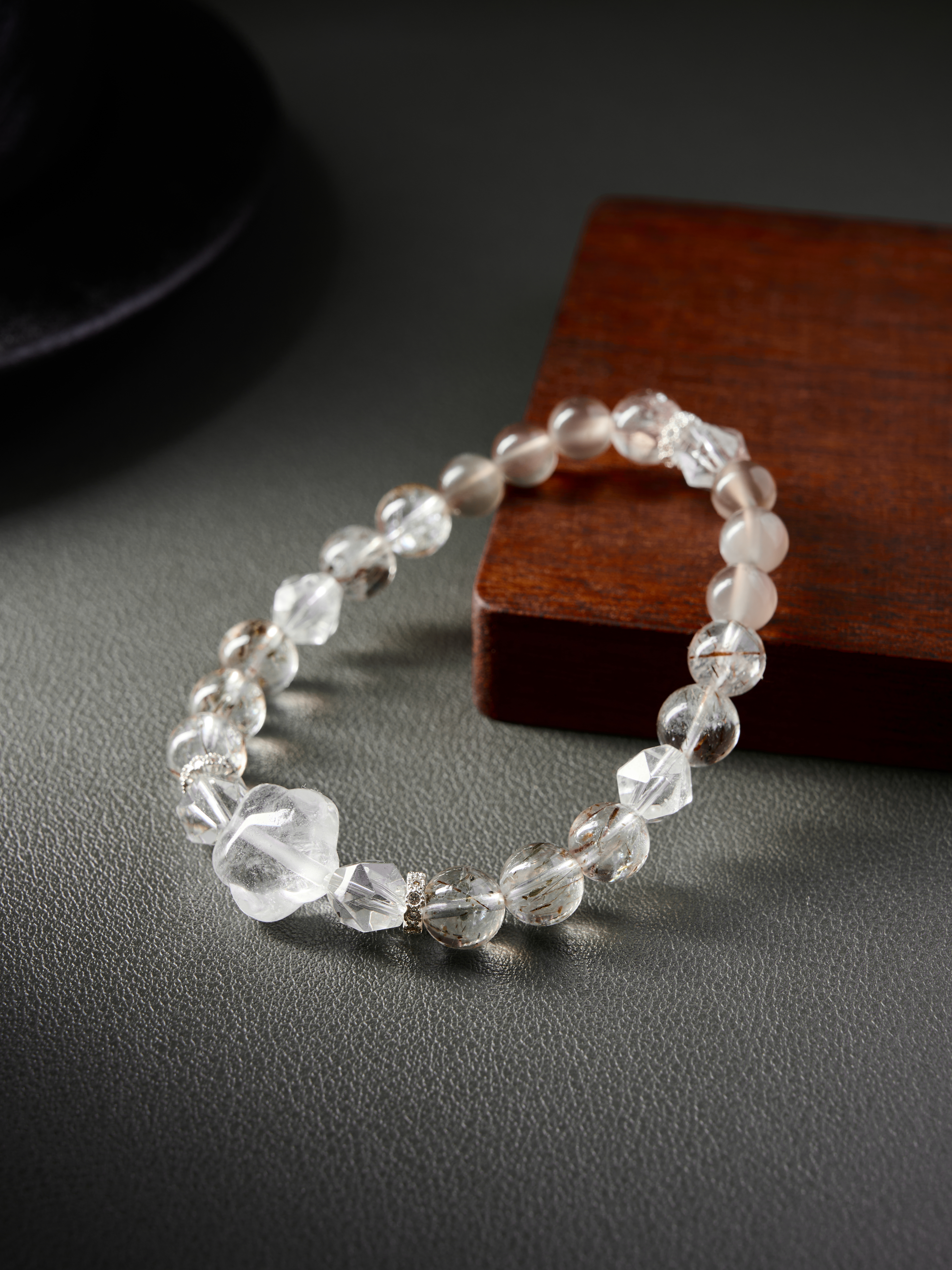 Macro side angle contrasting faceted clear quartz with smooth rutilated and rose quartz rounds