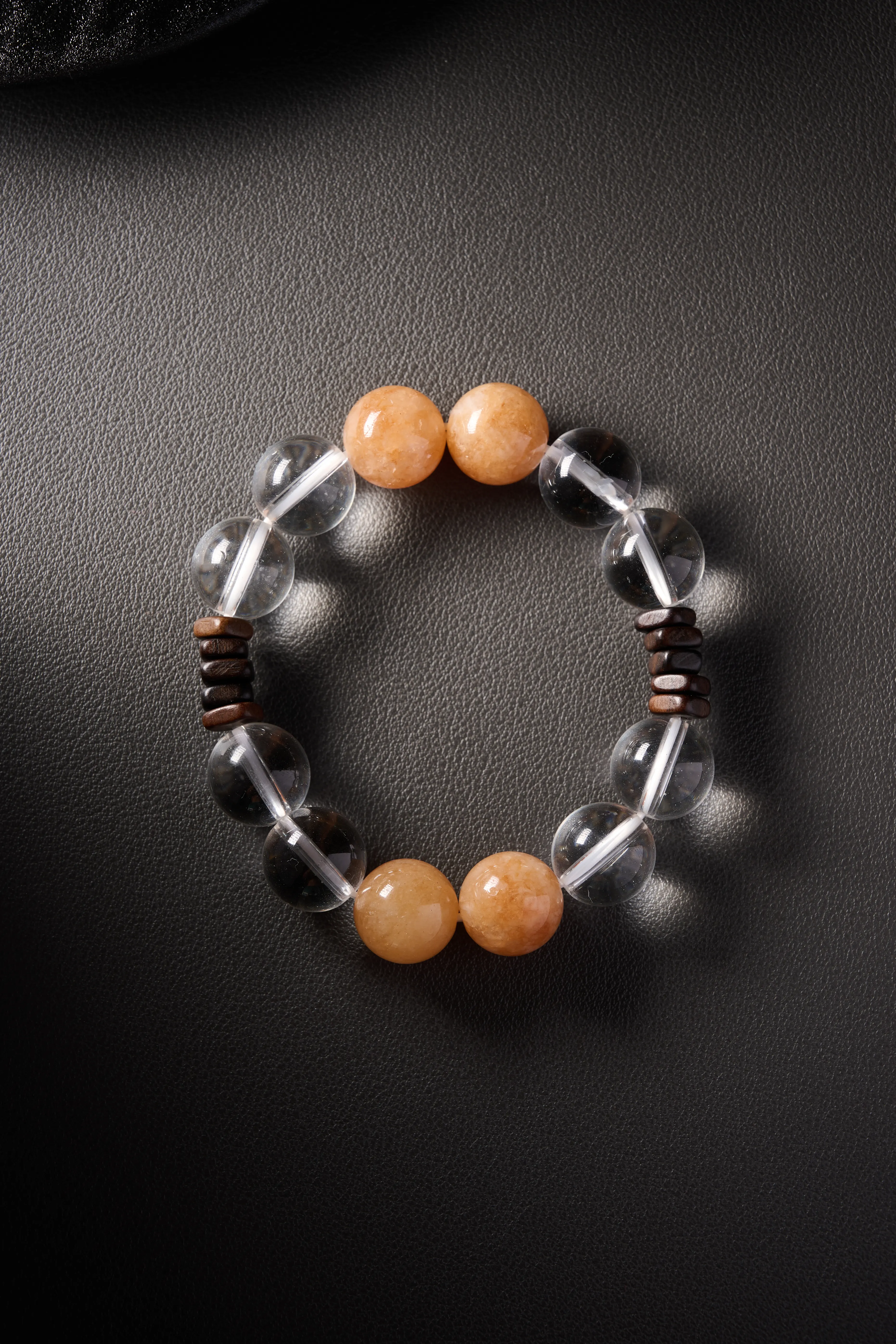 Hero image – clear quartz and yellow jade beaded bracelet on wooden display, minimalist dark background.