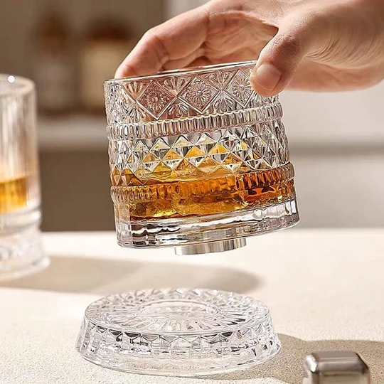 Whiskey glass being lifted from its rotating crystal base