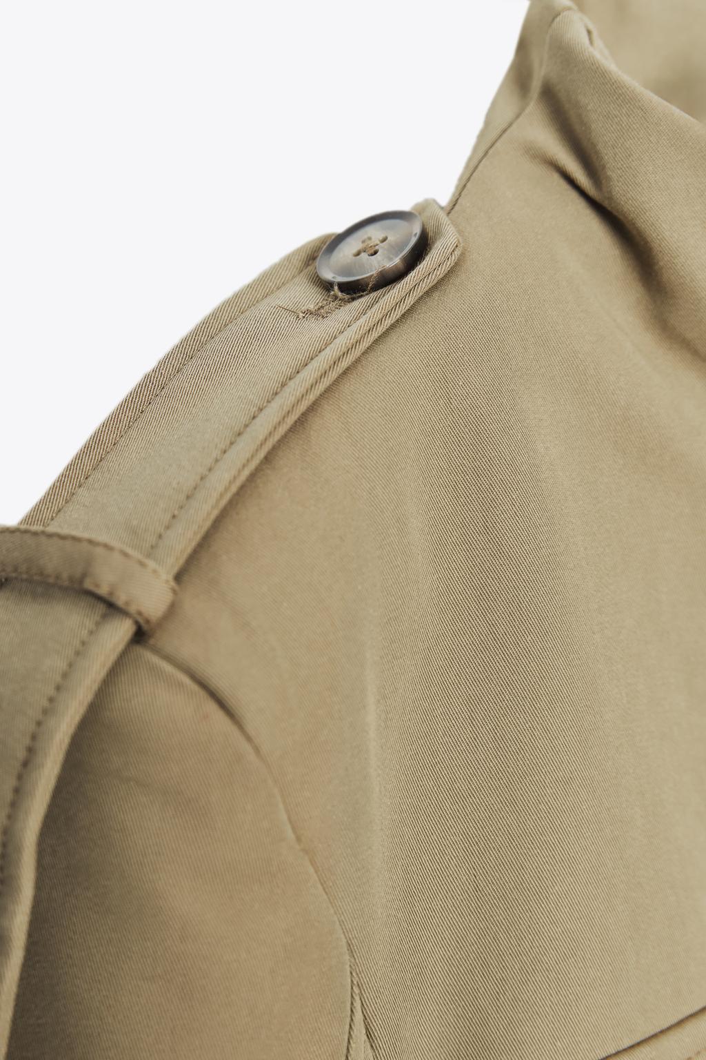 "Detail of epaulet with button on light khaki jacket."