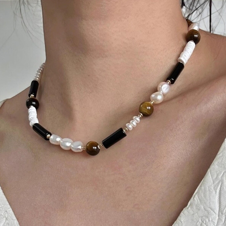 Natural freshwater pearl and tiger eye beaded necklace on white background. 