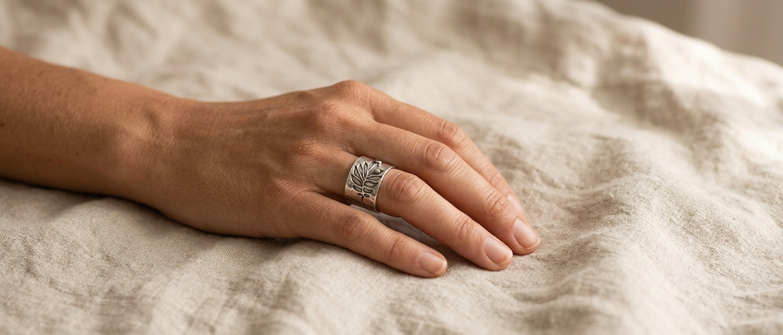 Hand wearing a delicate ring resting on linen