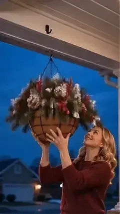 Woman hanging Christmas basket on porch hook
