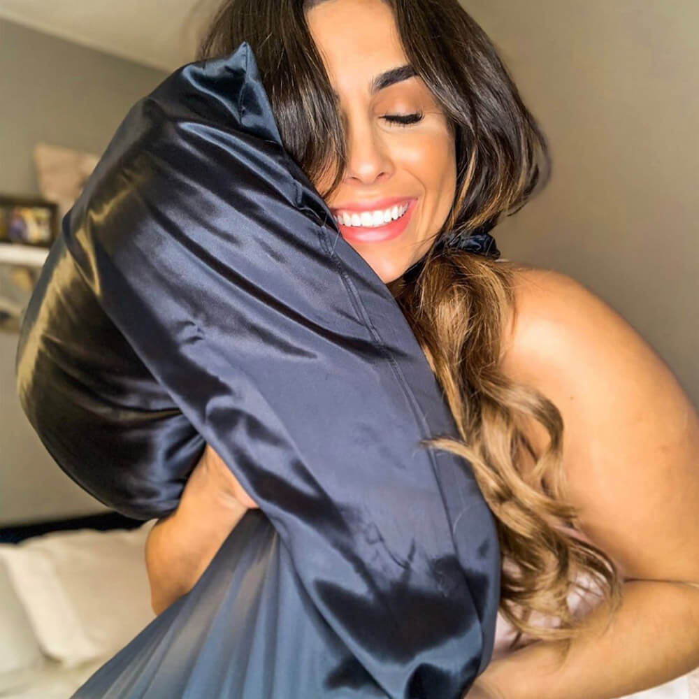Smiling woman hugging her blue Blissy silk pillowcase