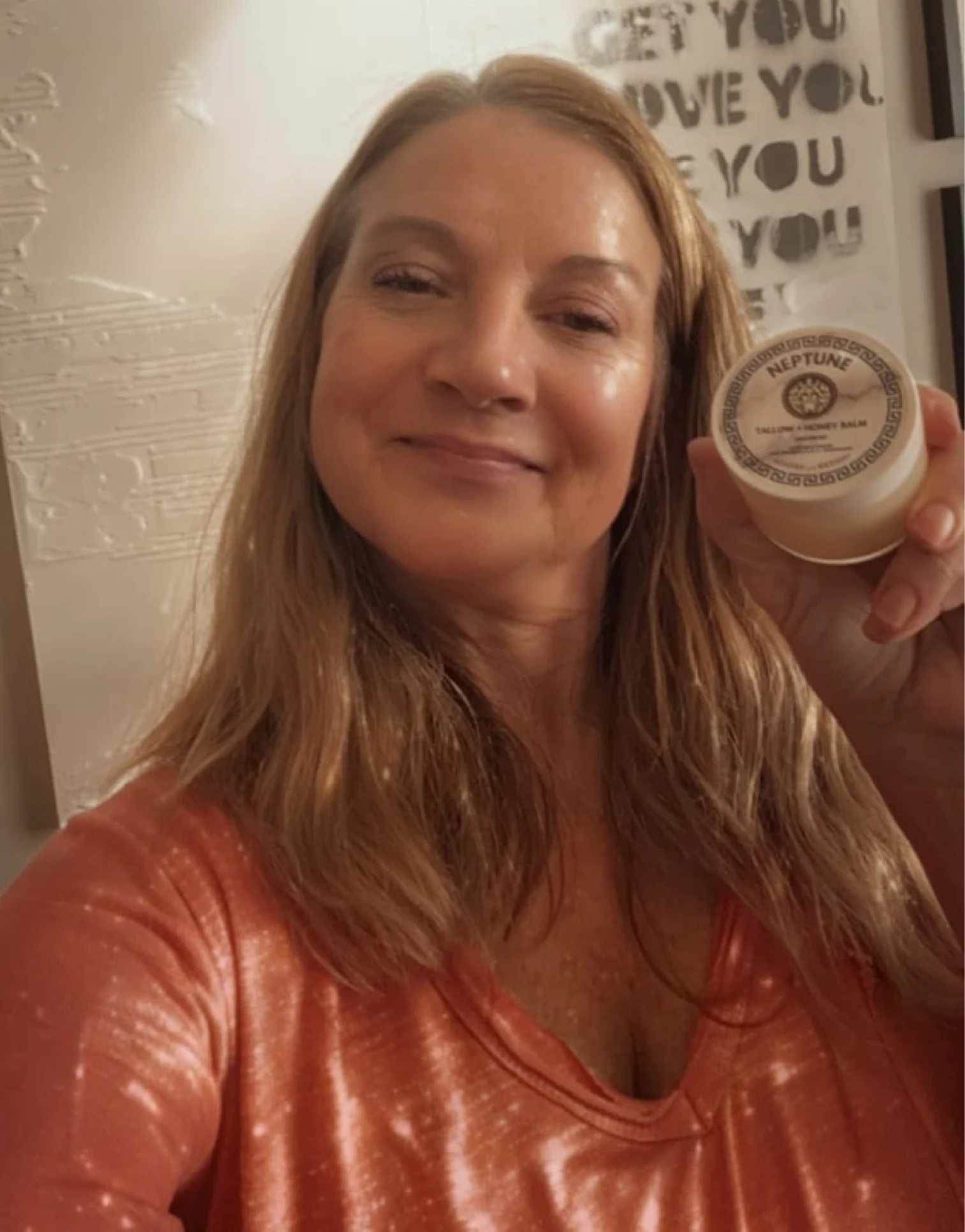 Person smiling, holding a jar labeled 'Neptune' with text on wall behind.