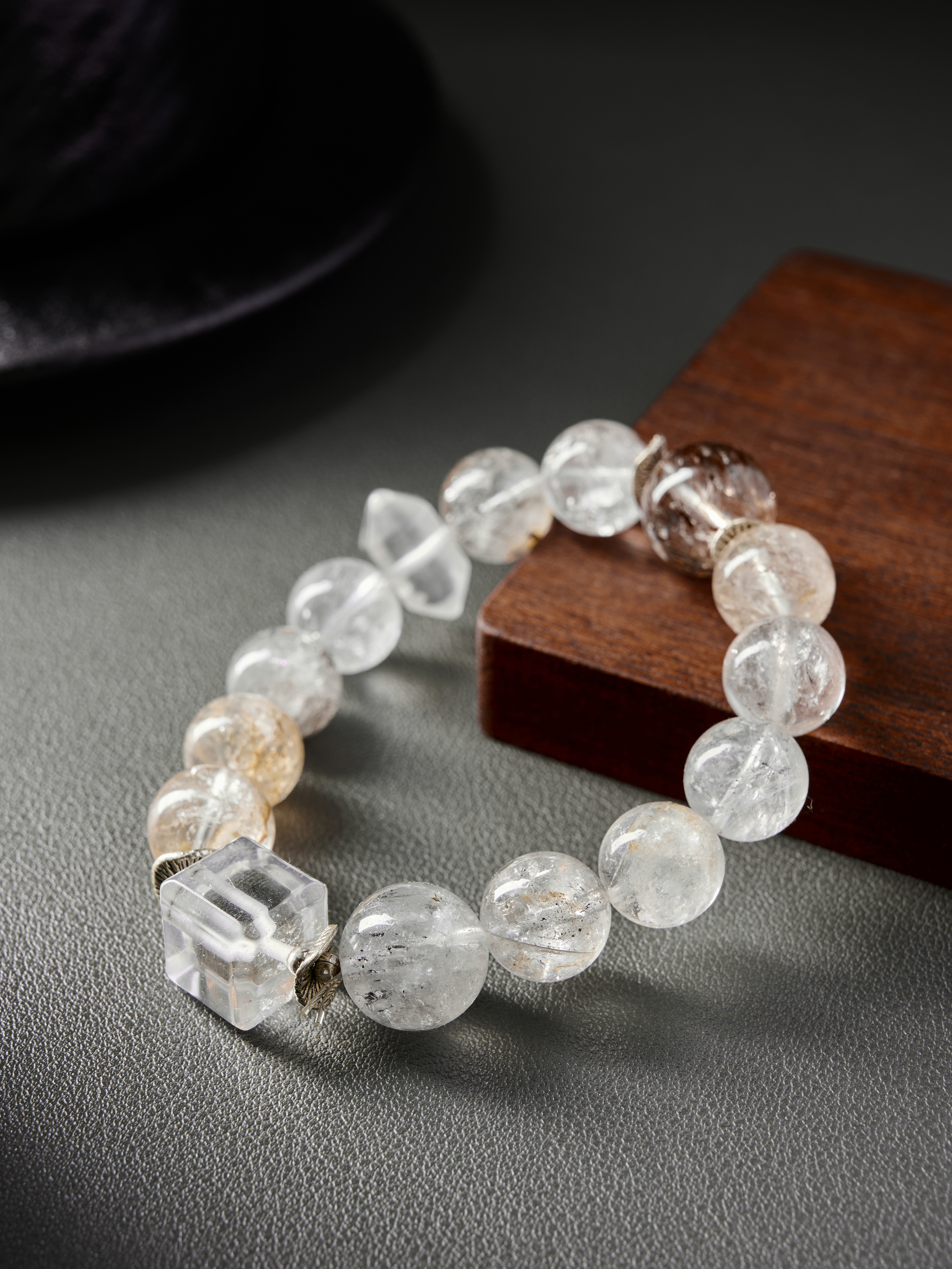 Hero image – natural rutilated quartz beaded bracelet on gray background, clear and golden inclusions.
