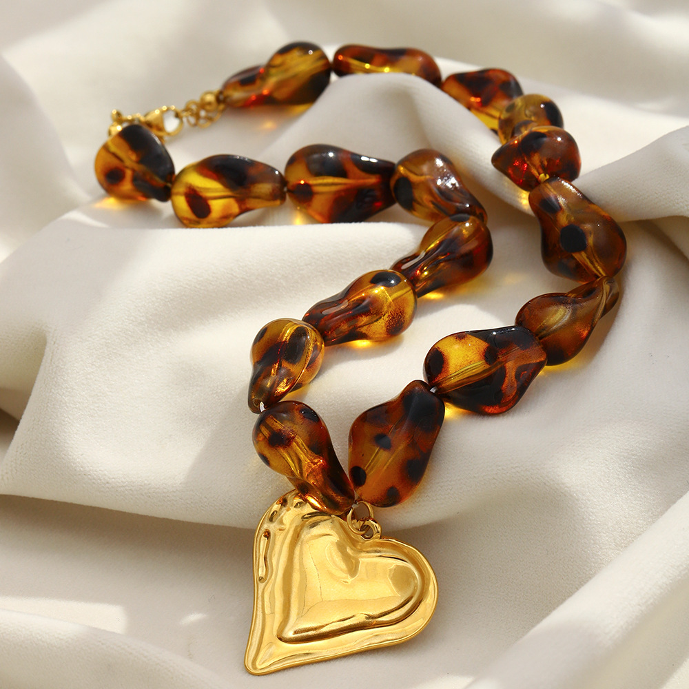 Simple yet luxurious this popular vacation necklace features a stainless steel heart-shaped acrylic piece plated with 18K amber