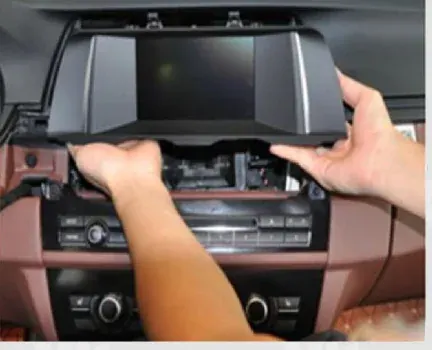 Original BMW F10 iDrive display being lifted out of the dashboard
