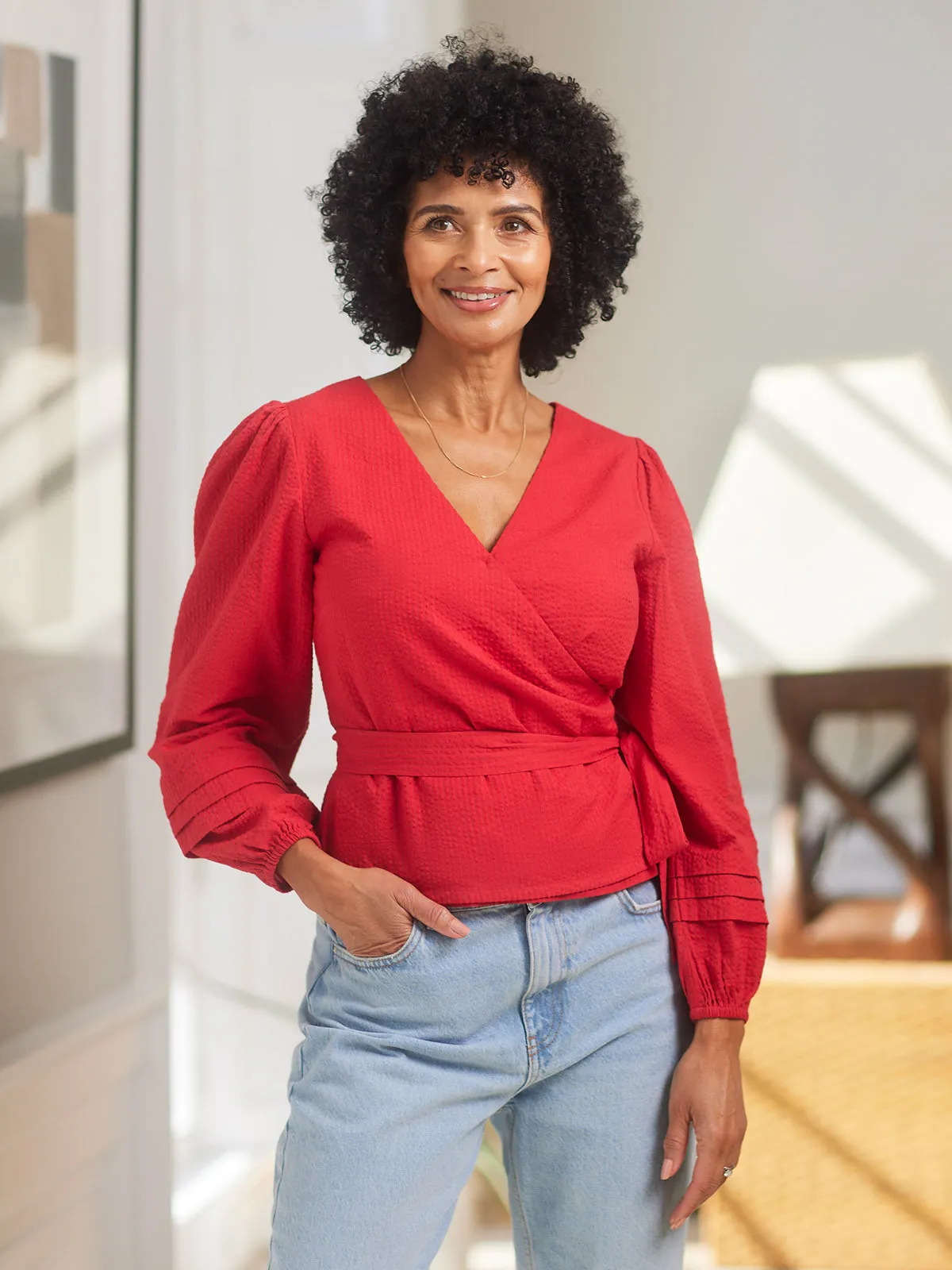 Woman wearing a red wrap blouse with mom jeans