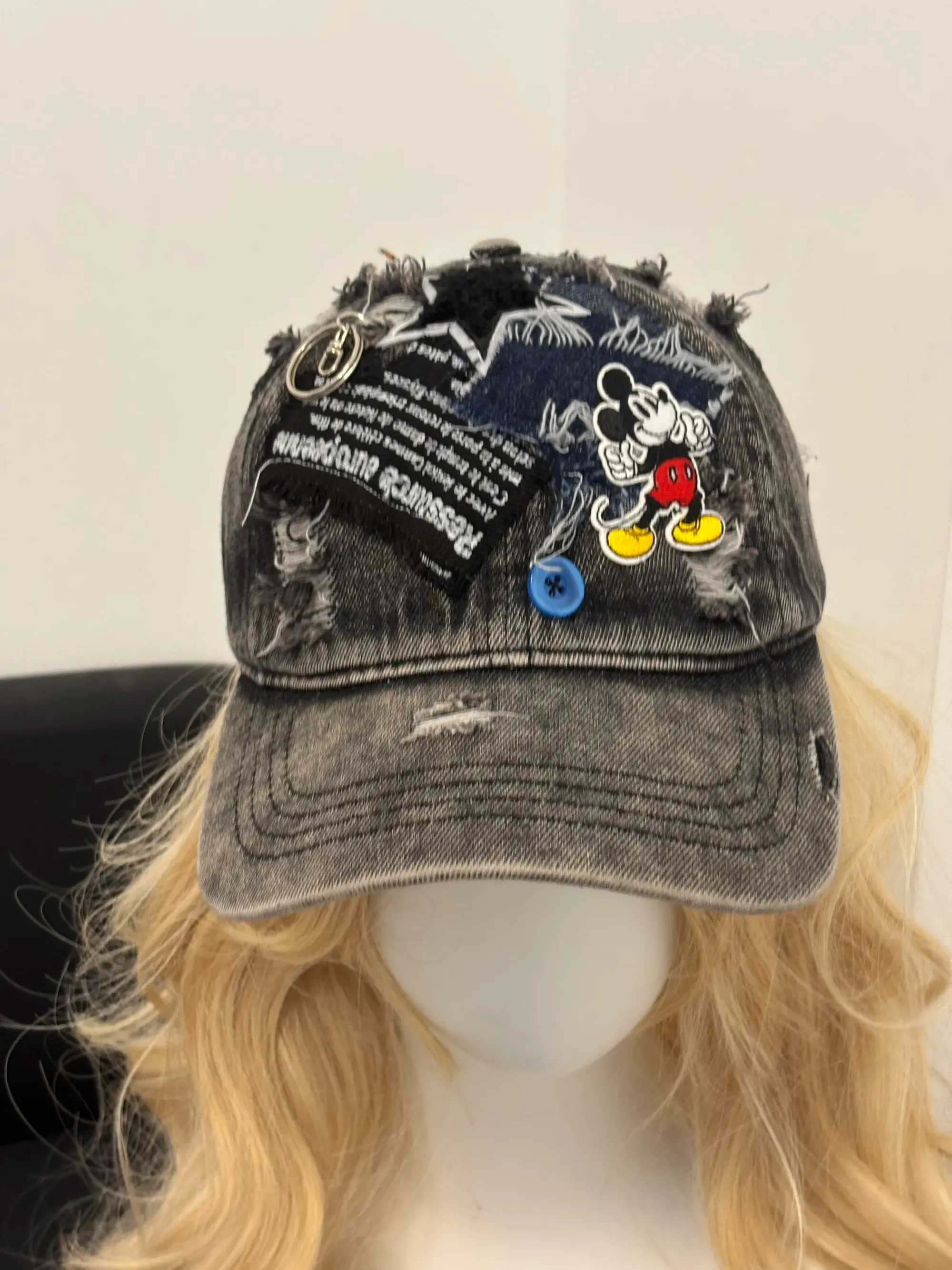 High-fashion shot of a woman in a black dress wearing an avant-garde deconstructed straw sun hat.