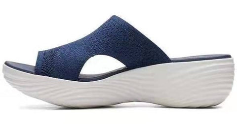 Seitenansicht einer blauen Sandale mit offenen Zehen, gestricktem Obermaterial und dicker weißer Sohle.