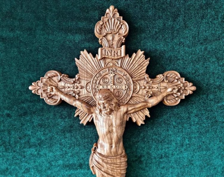 A wood carving of a crucifixion cross with a pattern of Saint Benedict’s exorcism