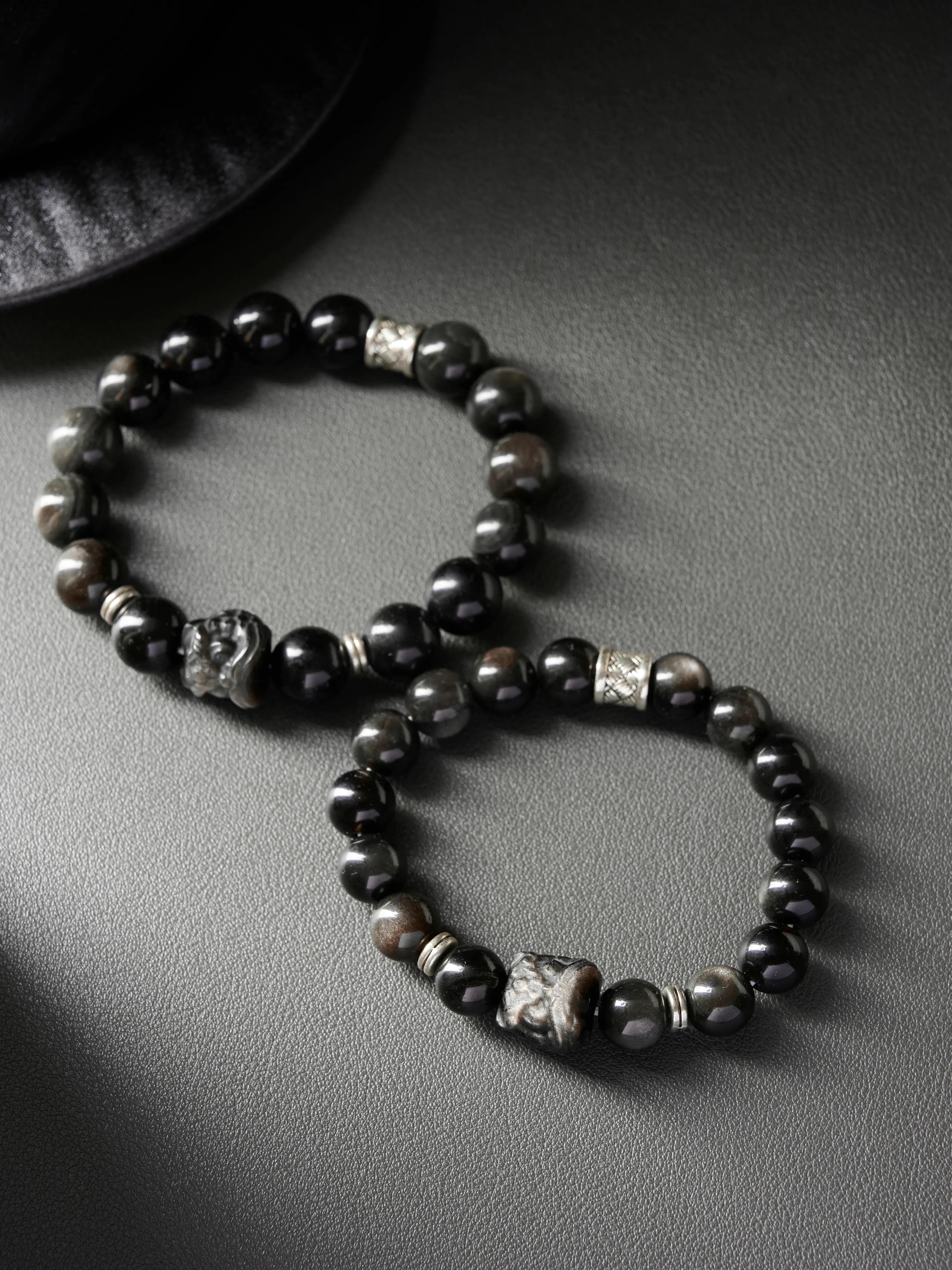 Flat lay circle composition showing carved focal bead on each bracelet, minimalist black design