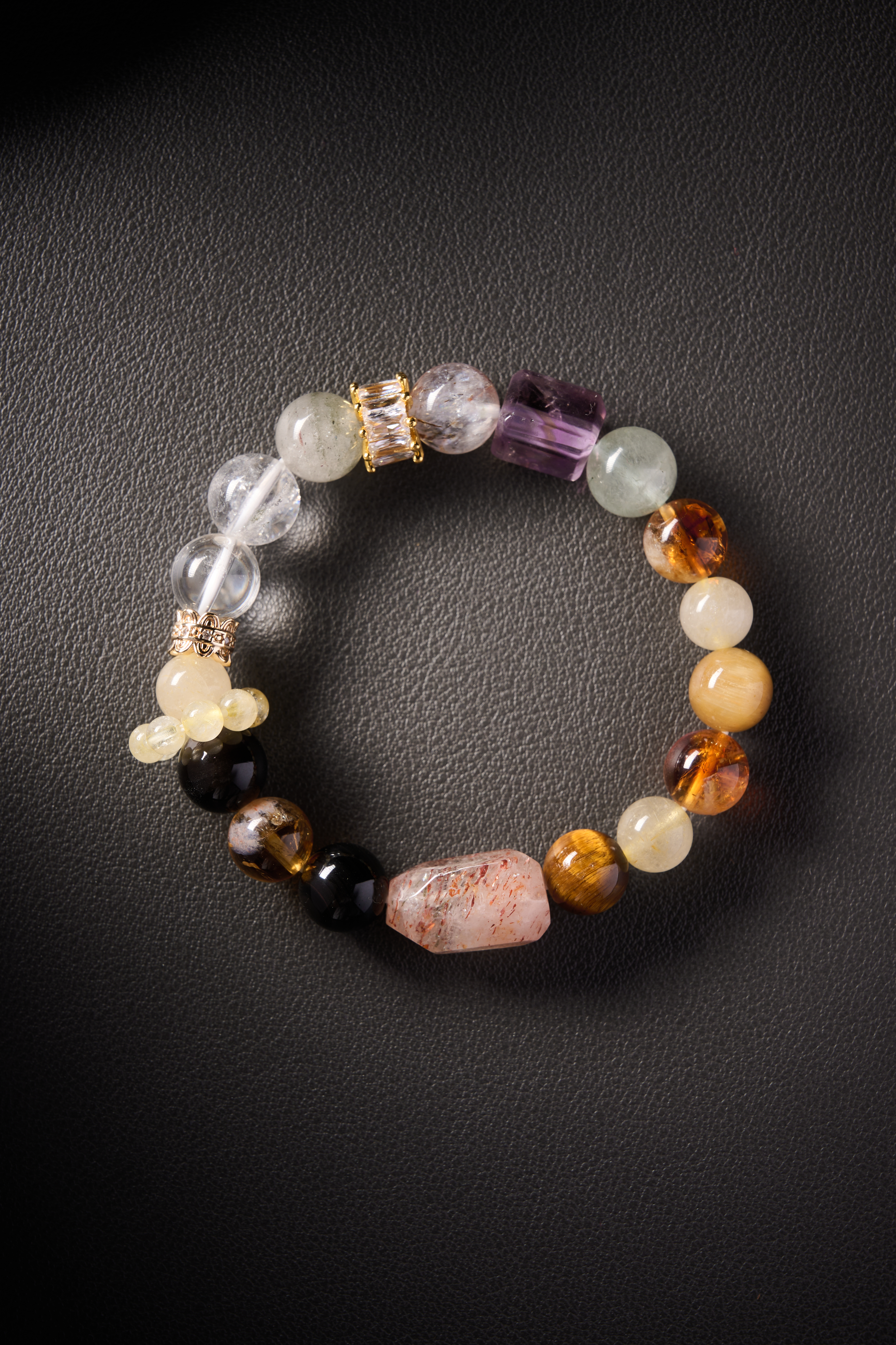Hero image – multi-crystal energy bracelet with clear quartz, amethyst, citrine, yellow jade, tiger’s eye and obsidian on dark background.