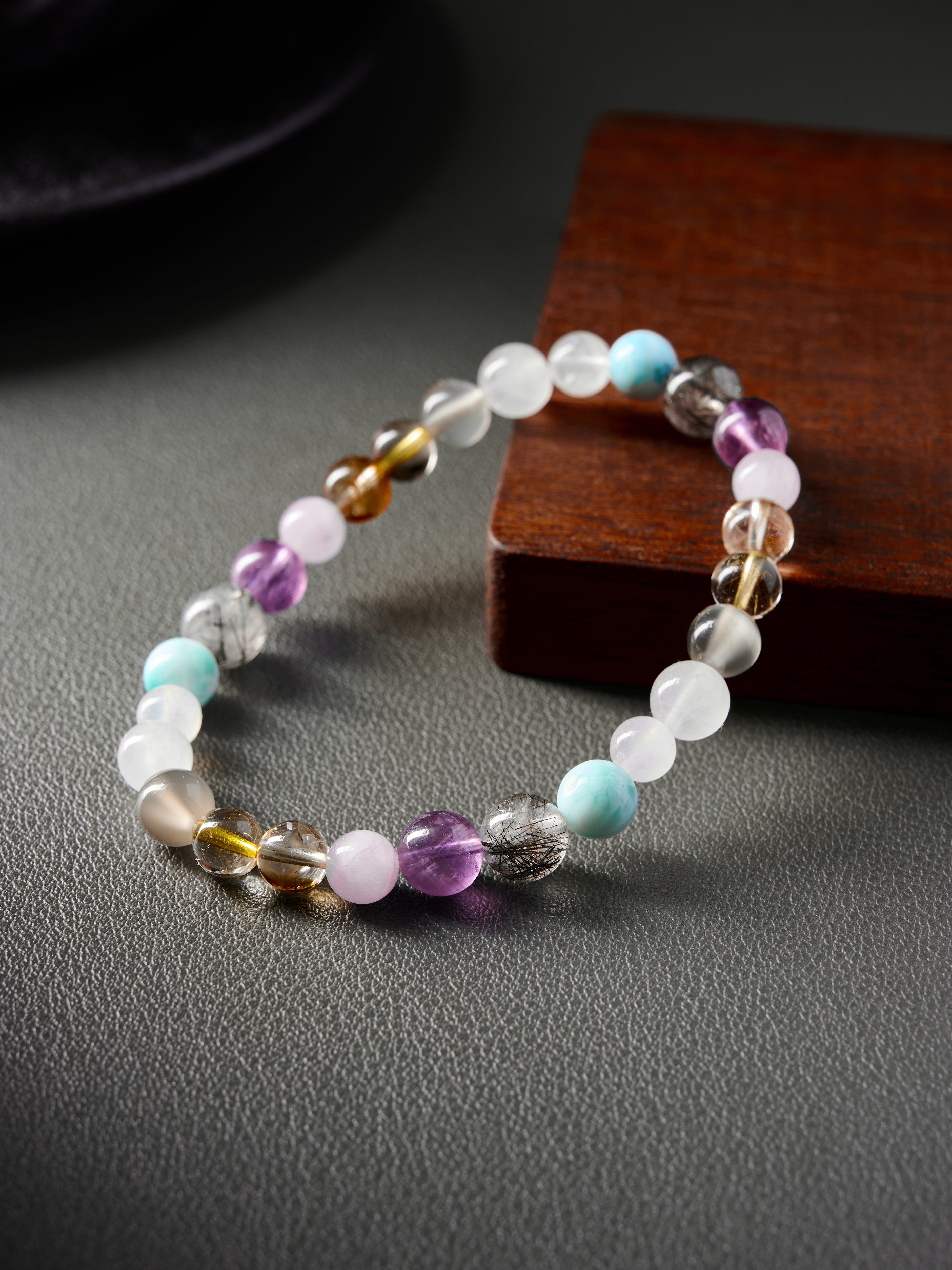 Angled side shot highlighting rutilated-quartz needles and pale pink kunzite with hand-strung spacing
