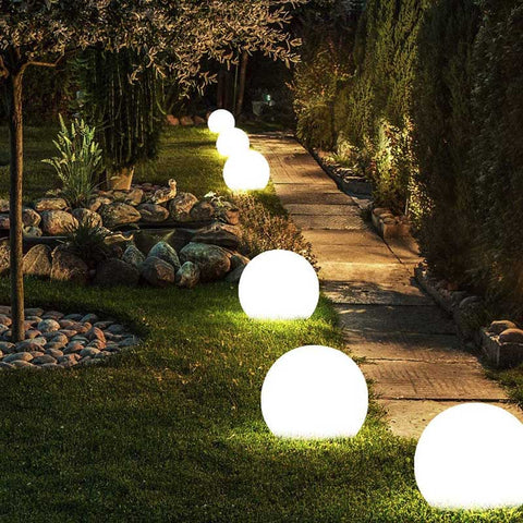 Glowing, round solar lights illuminate a garden path at night.