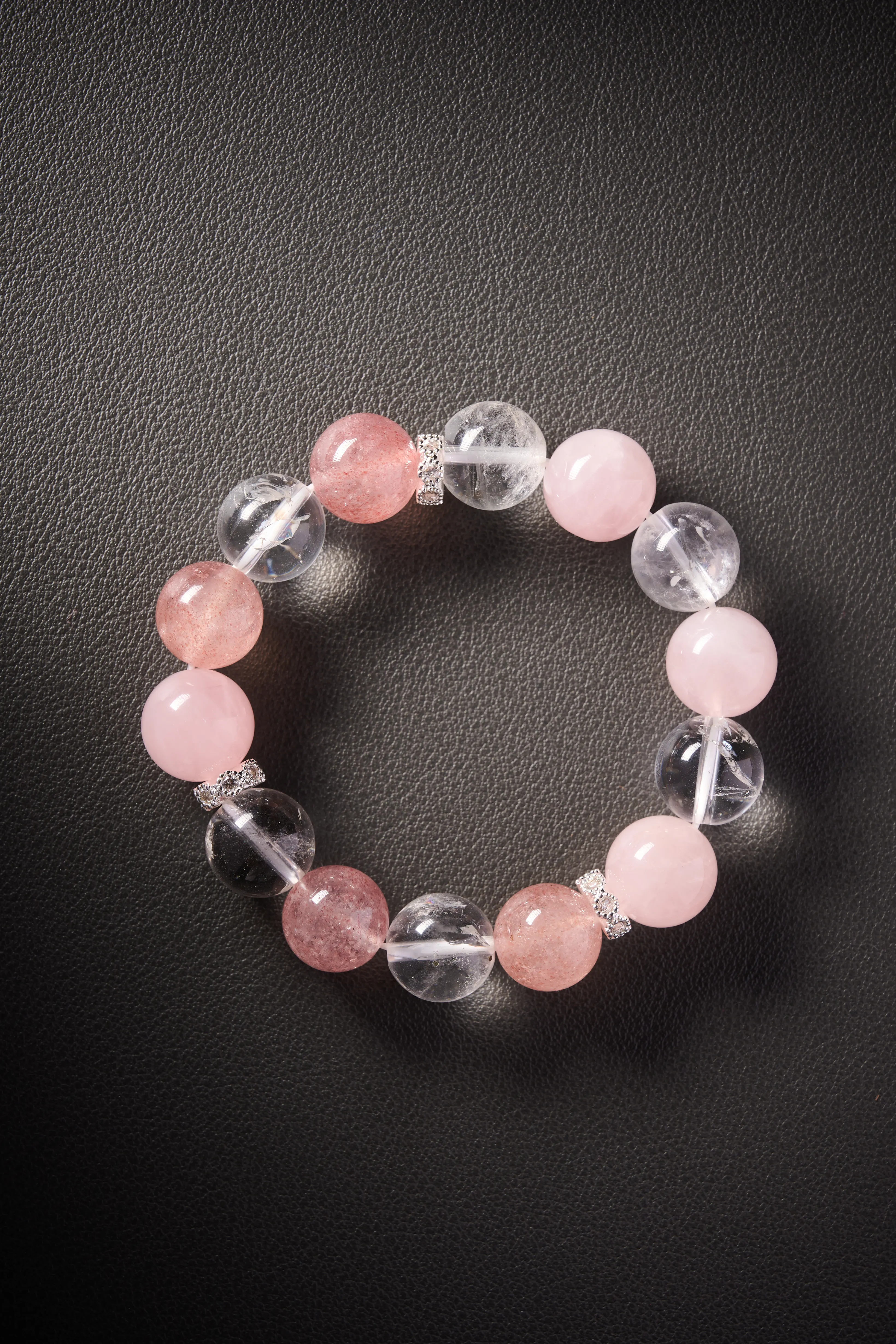 Hero image – clear quartz, rose quartz and strawberry quartz beaded bracelet on dark background, polished round beads.