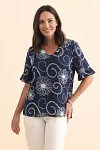 Front view of woman wearing a navy blue V-neck blouse with intricate cream floral embroidery and ruffle sleeves