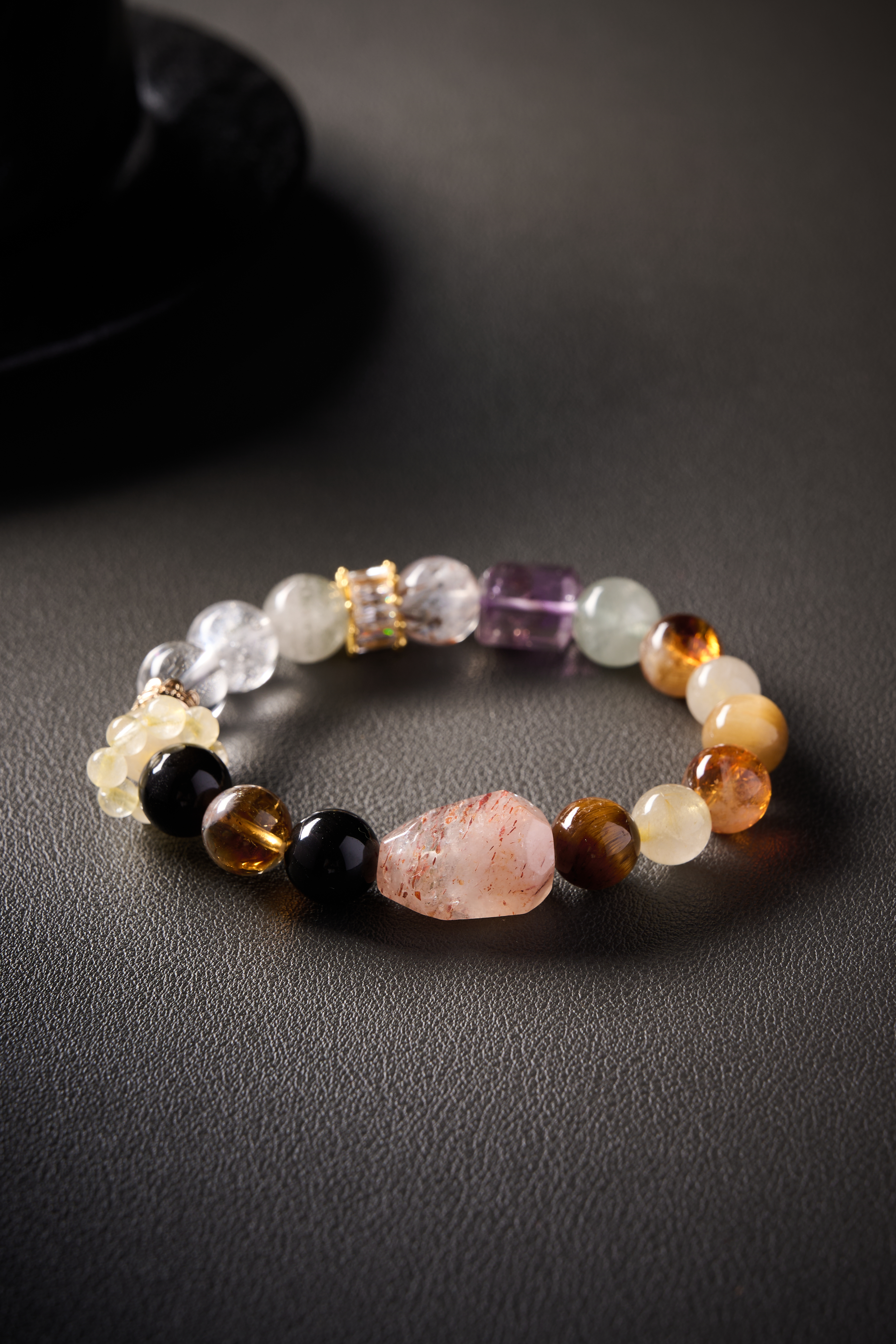 Close-up of gemstones – polished round beads showing amethyst purple, citrine gold and clear quartz transparency.