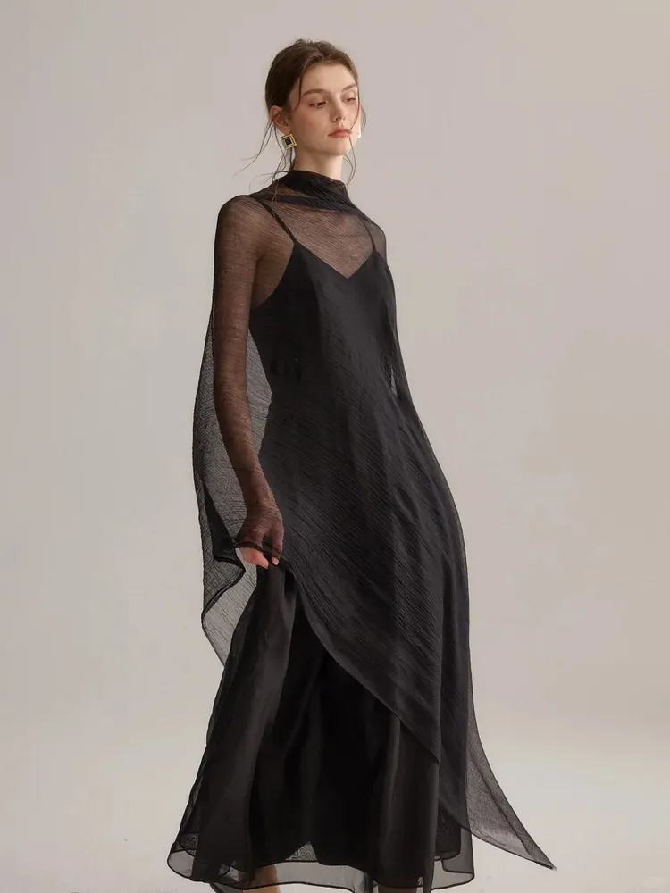 A black spaghetti strap dress layered over a light, semi-transparent tulle shawl.
