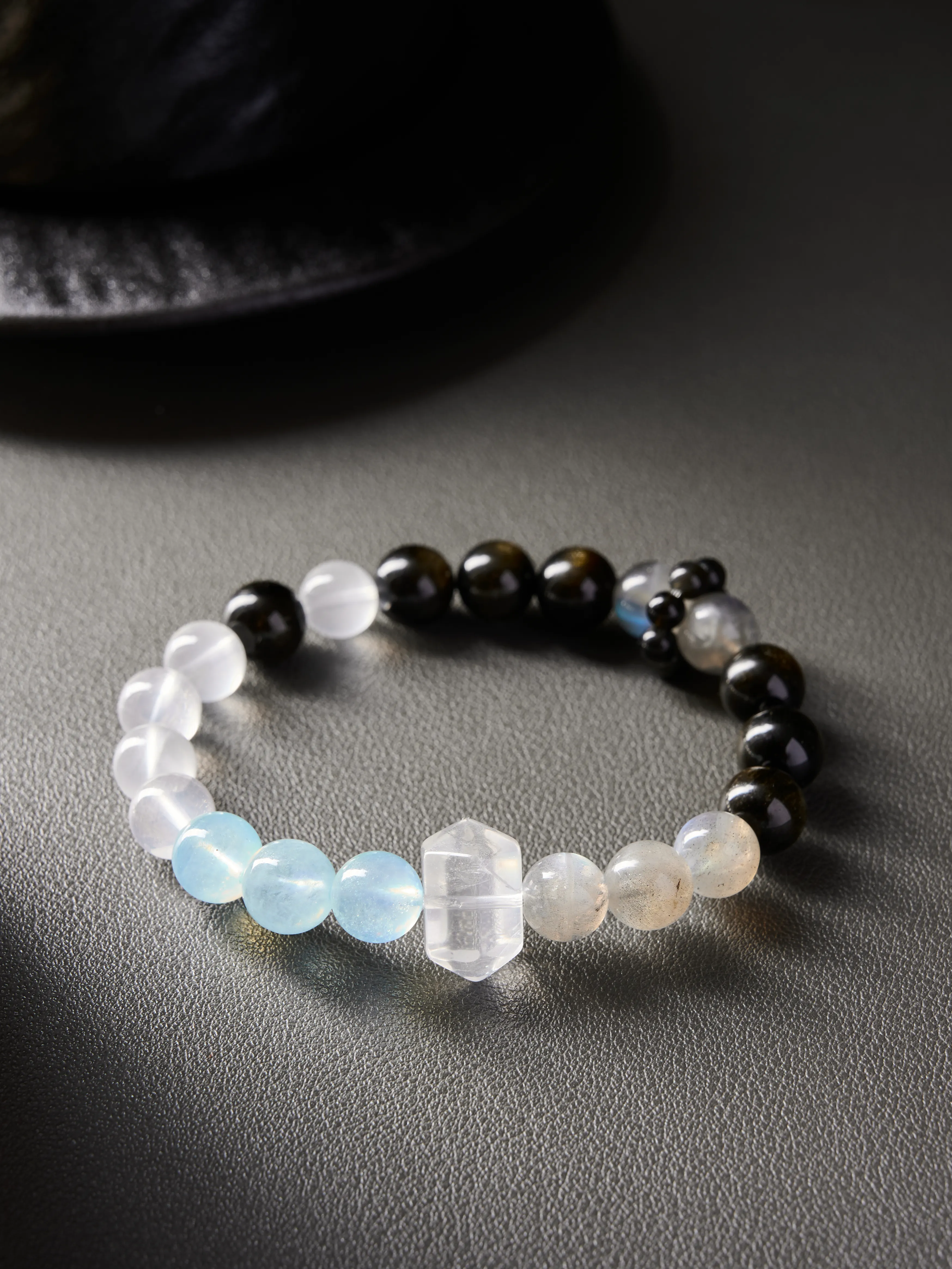 Complete bracelet layout on neutral background, natural grey moonstone and obsidian beads