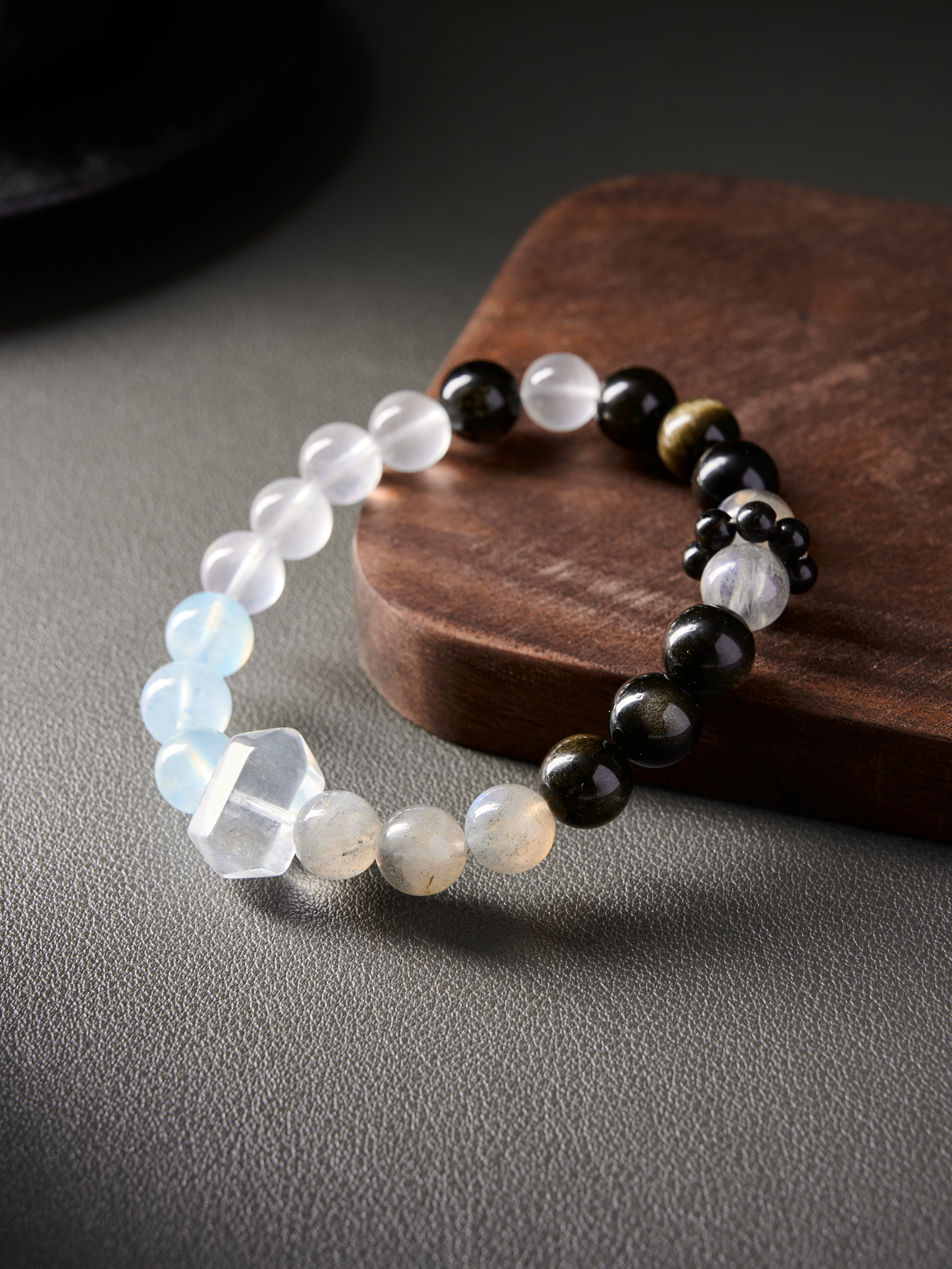Side angle showing bead spacing and polish on obsidian and grey moonstone, hand-strung bracelet
