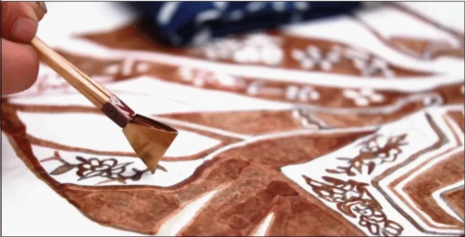 Drawing hot wax on batik fabric