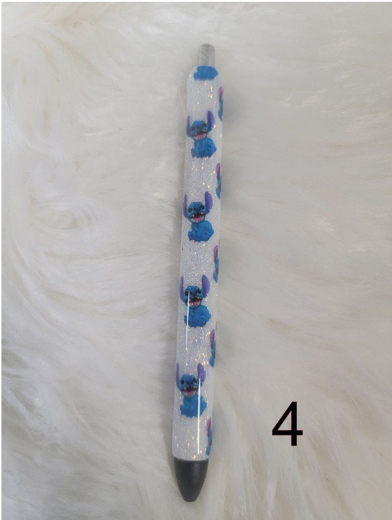 May include: A white pen with blue glitter and a repeating pattern of blue Stitch characters. The pen has a black tip and is labeled with the number '4'.