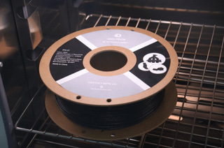 高性能3D打印用QIDI PPS-CF碳纤维增强聚苯硫醚复合耗材线轴置于打印平台上，标签展示材料特性