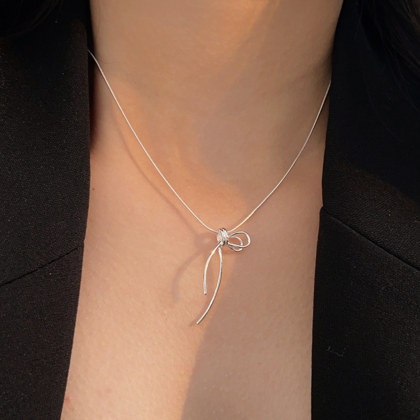 Side view of the minimalist ribbon bow necklace.