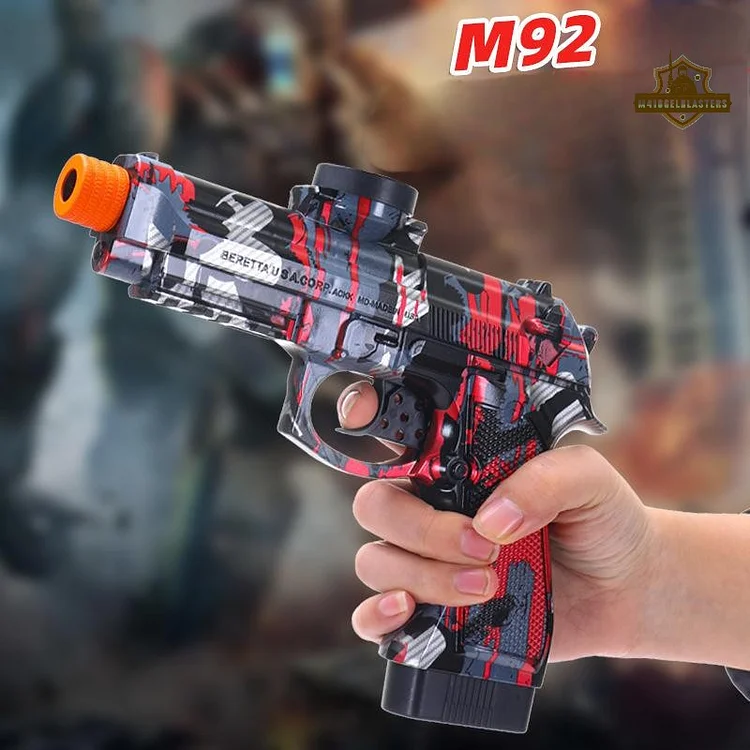 Hand gripping graffiti-red M92 full-auto gel pistol, showing trigger and magazine ready to fire.