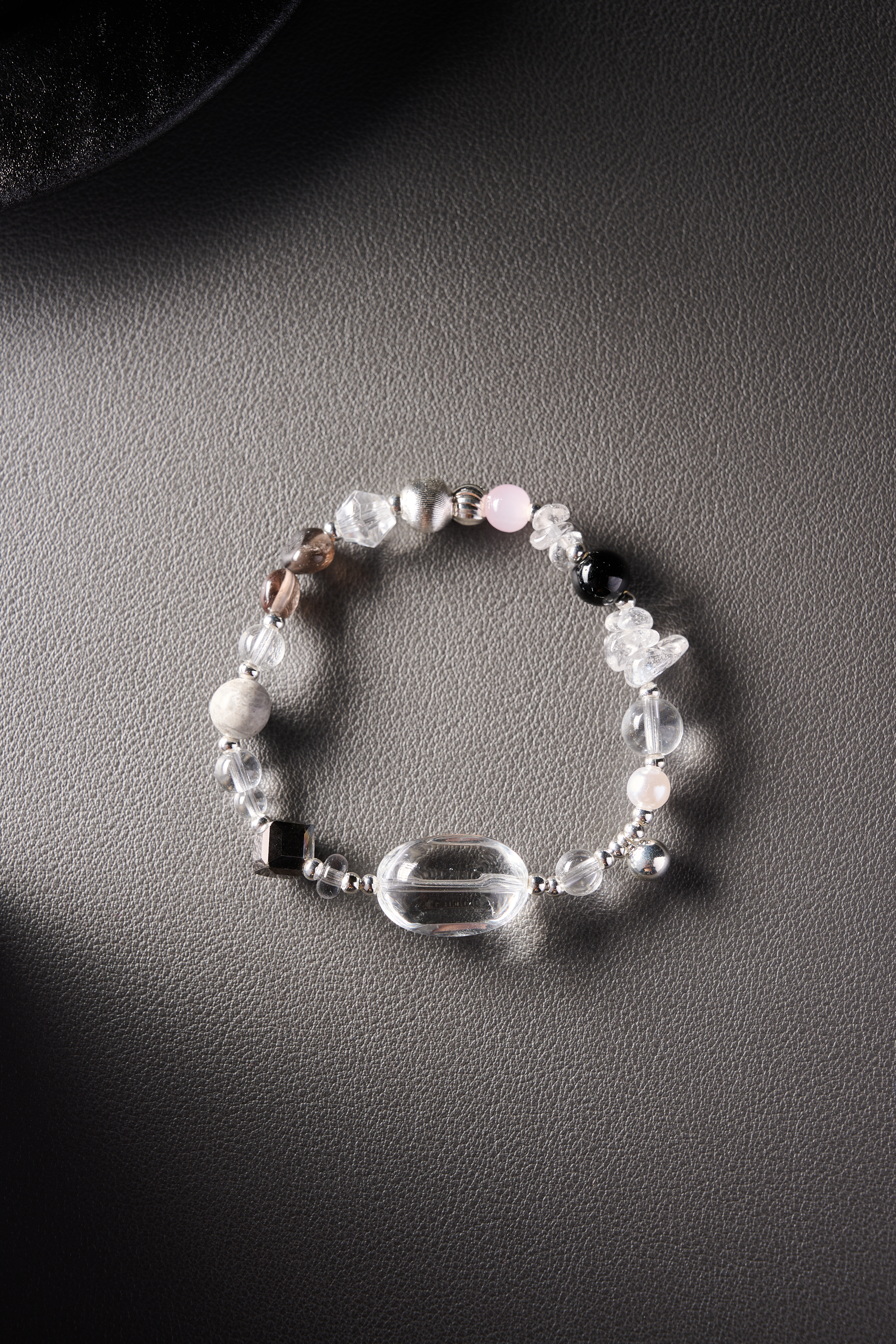 Main view – rose quartz, smoky quartz, and clear quartz bracelet on dark background.
