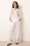 Front view of white linen two-piece set with floral embroidery on V-neck top and wide-leg pants